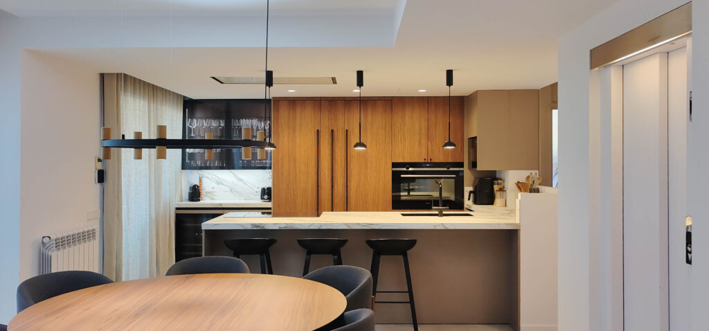 Cocina abierta al salón con frentes de madera y encimera en porcelánico Calacatta, colección RIGA de Armony Cucine, Barcelona